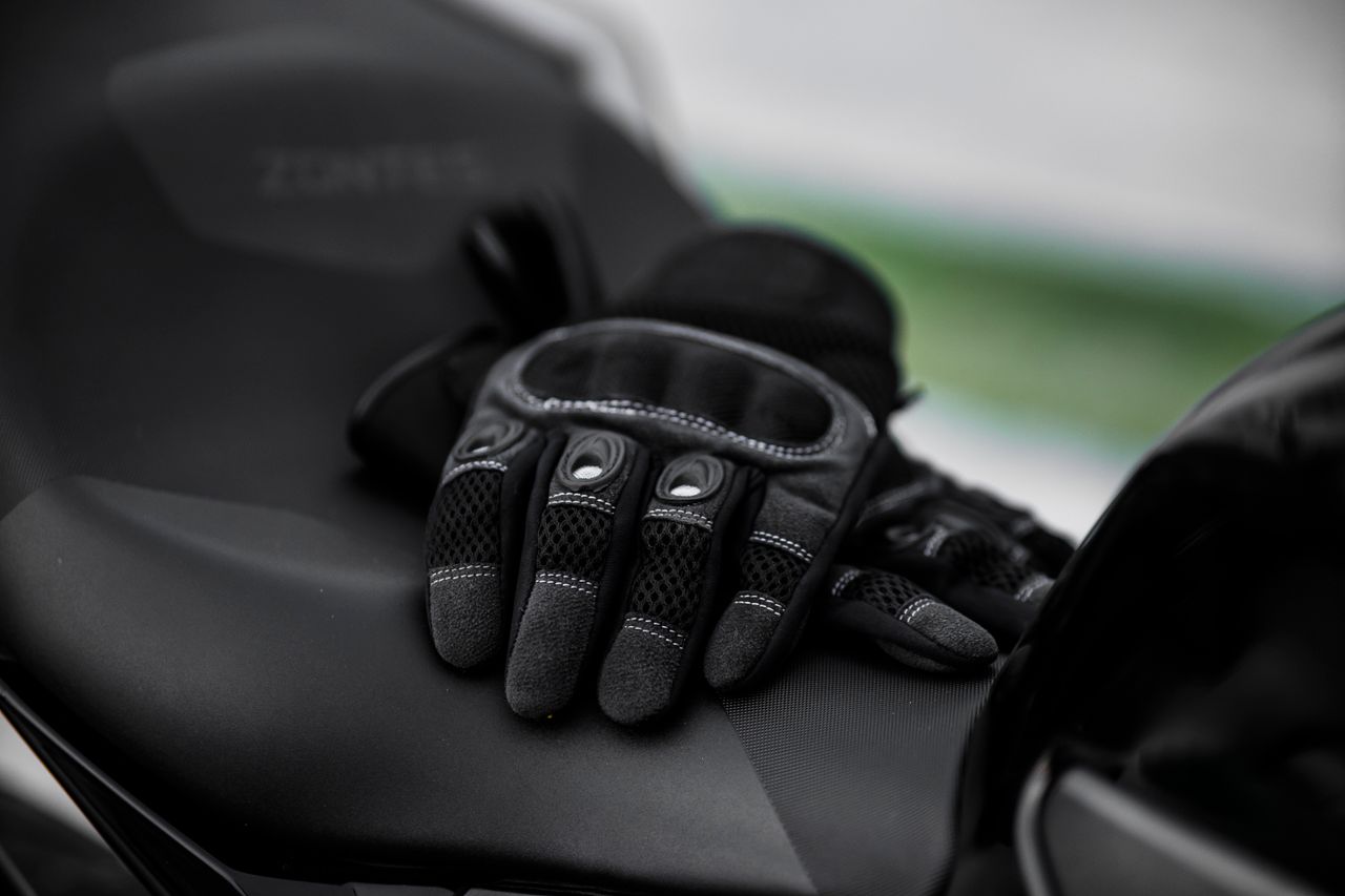 Home Close-up of black motorcycle gloves on a sleek motorcycle seat.