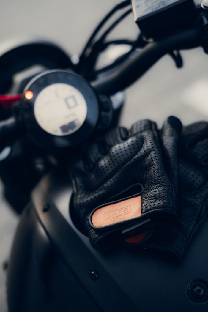 Home Detailed view of motorcycle handlebar with stylish leather gloves placed on it.